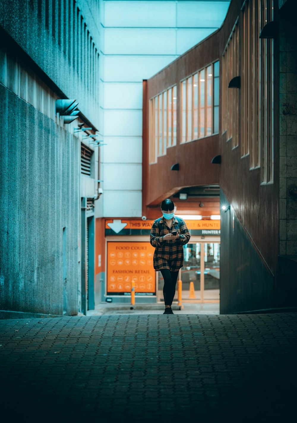 person in black jacket and black pants walking on sidewalk during daytime