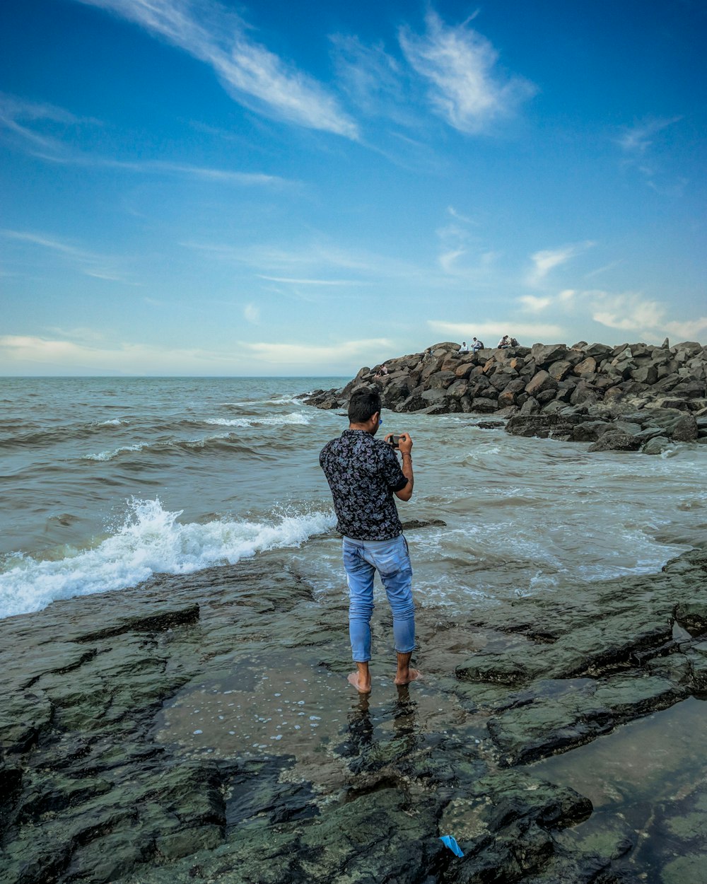 woman in blue denim shorts standing on rocky shore during daytime