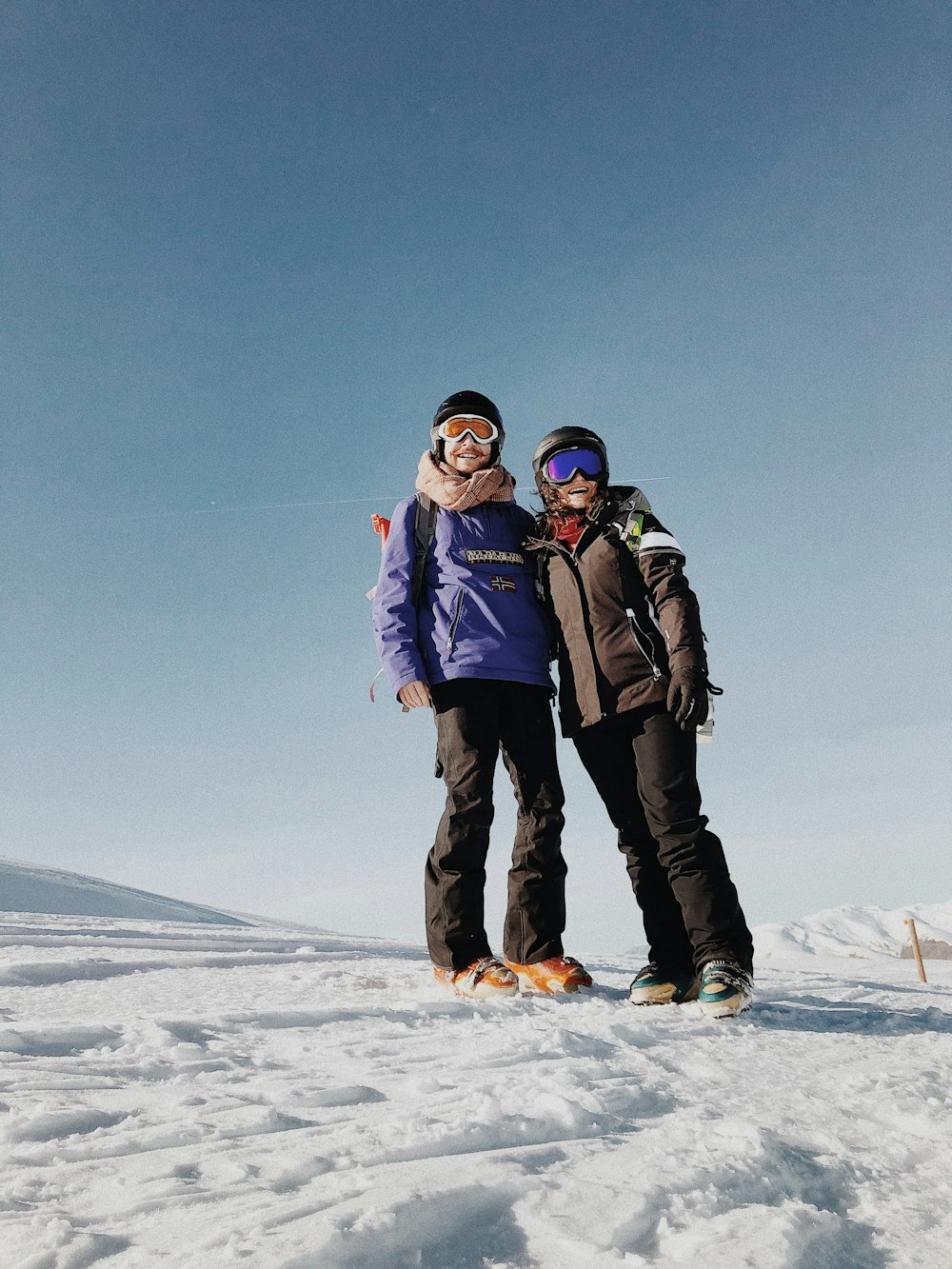 uomo e donna in piedi su terreno coperto di neve sotto cielo blu durante il giorno