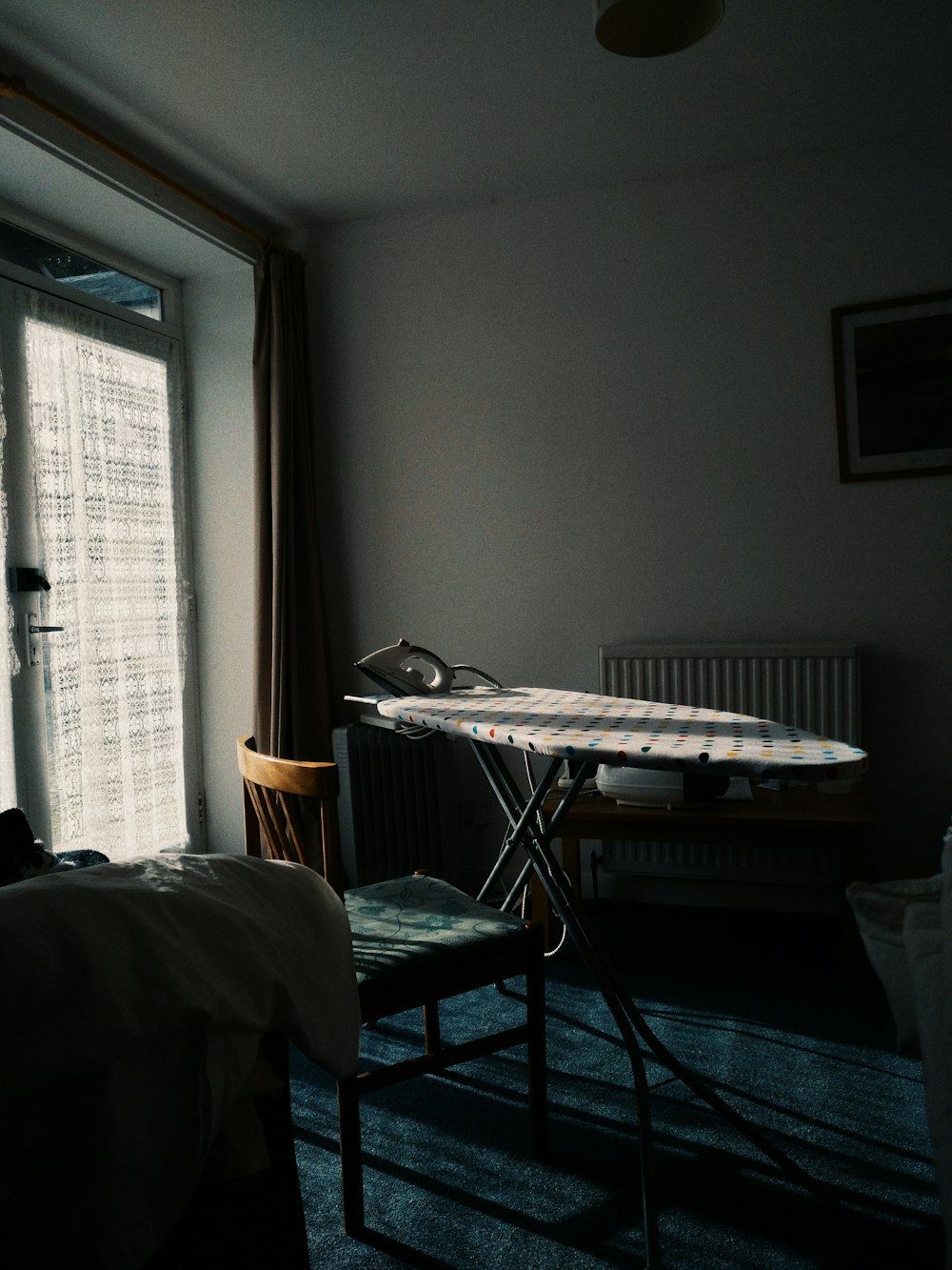 white and black ironing board beside white window blinds