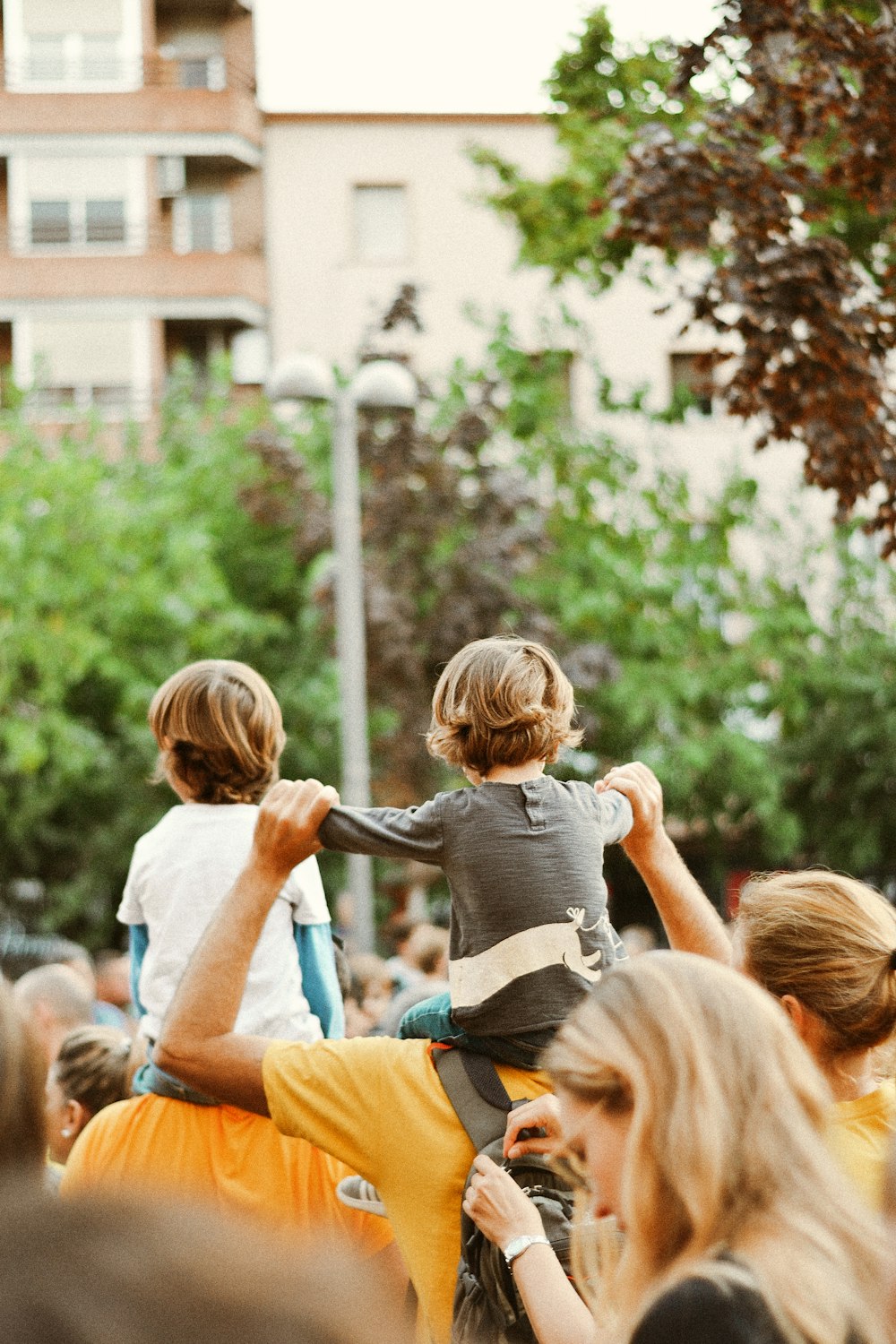 woman in gray t-shirt carrying child in blue and orange stripe t-shirt during daytime