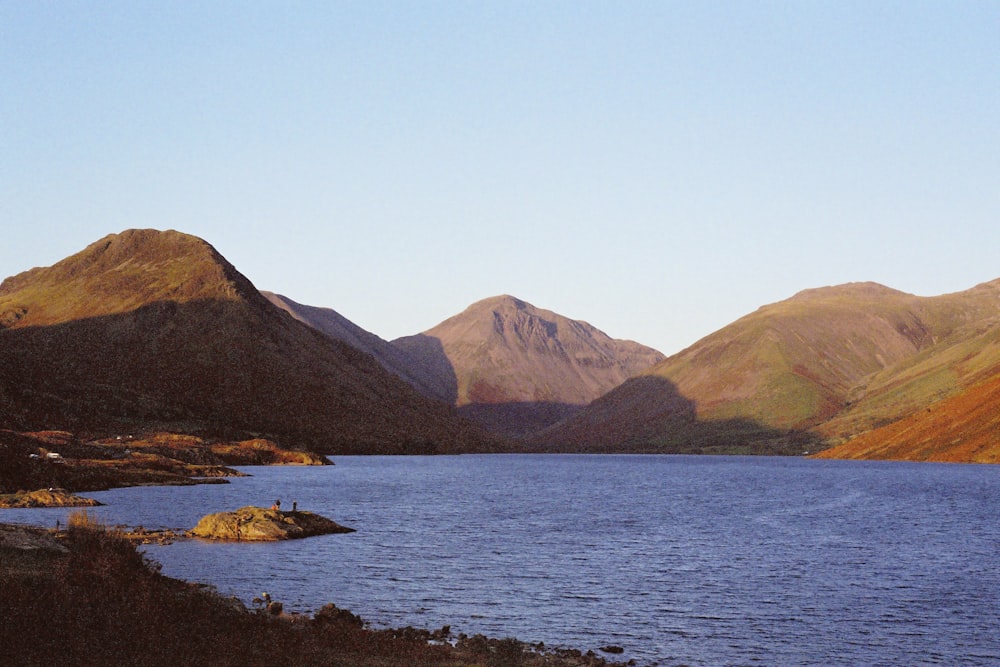 body of water near mountain during daytime