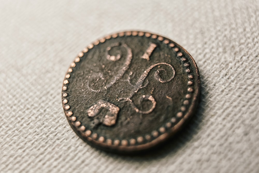 silver round coin on white textile