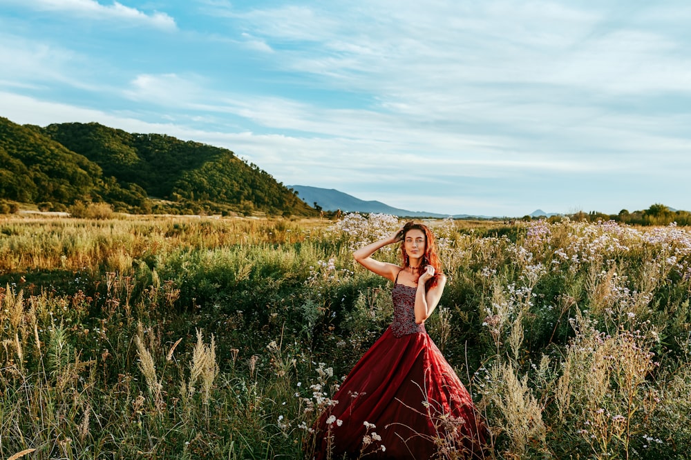 Frau in rotem ärmellosem Kleid, die tagsüber auf grünem Rasen steht