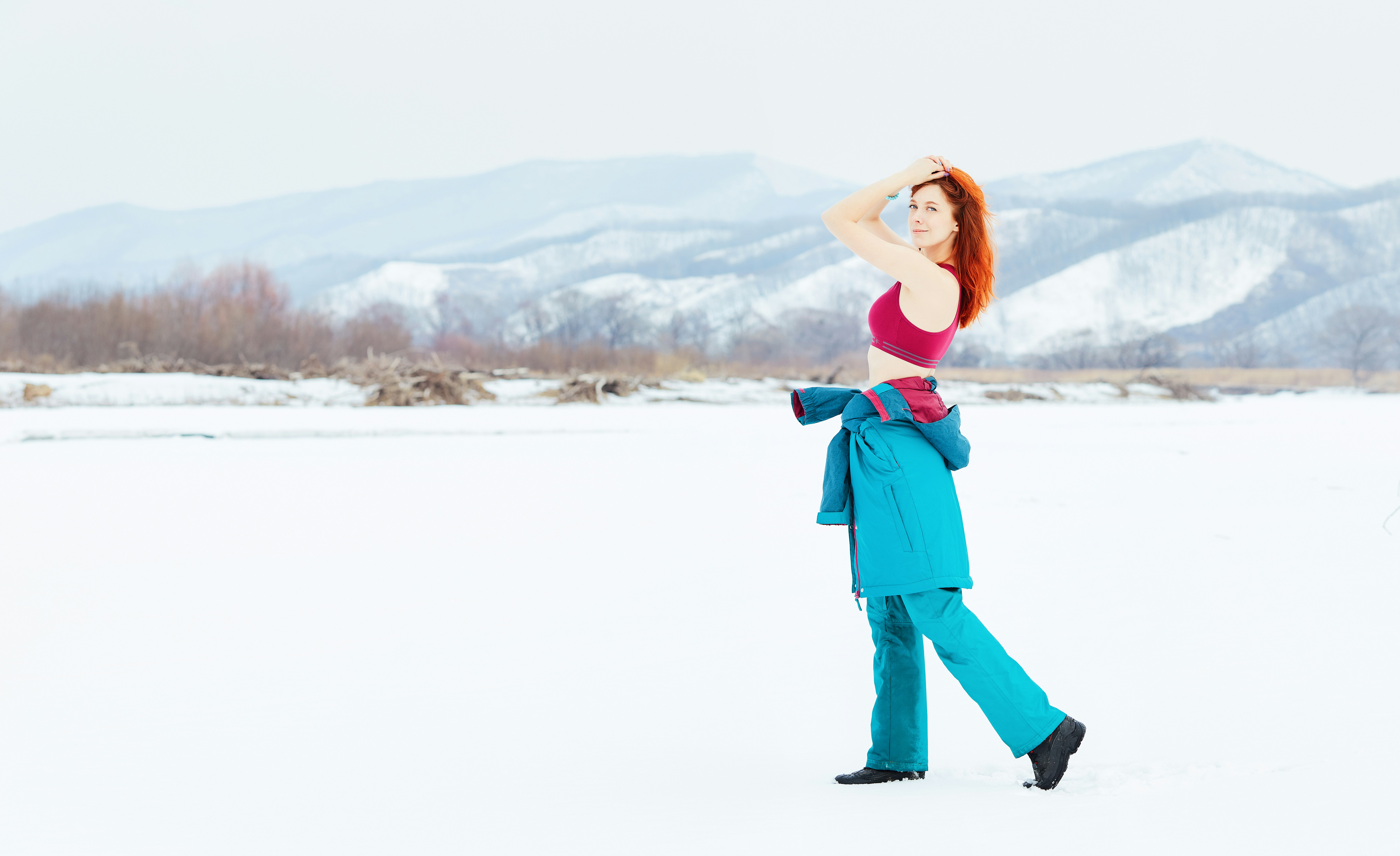 woman in green long sleeve shirt and black pants standing on snow covered ground during daytime