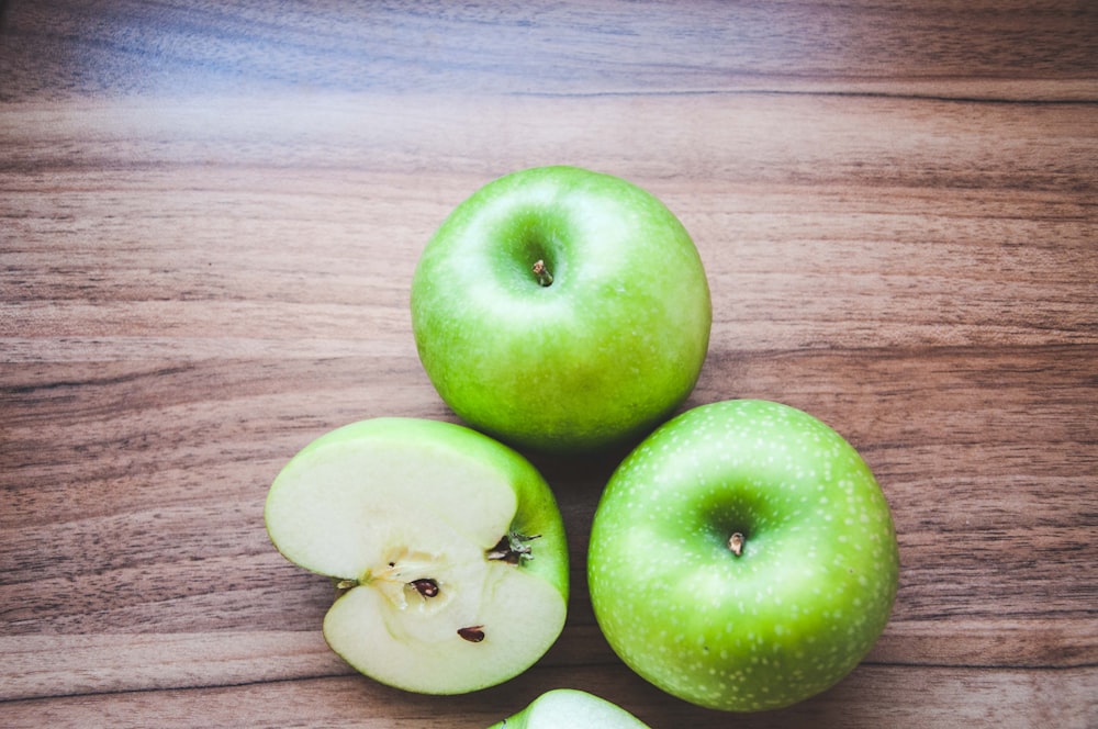 3 green apples on brown wooden table