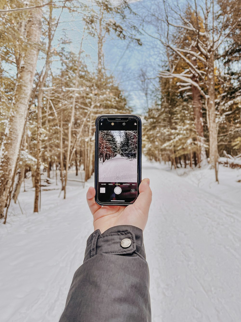 雪に覆われた地面の写真を撮る黒いiPhone 5を持っている人