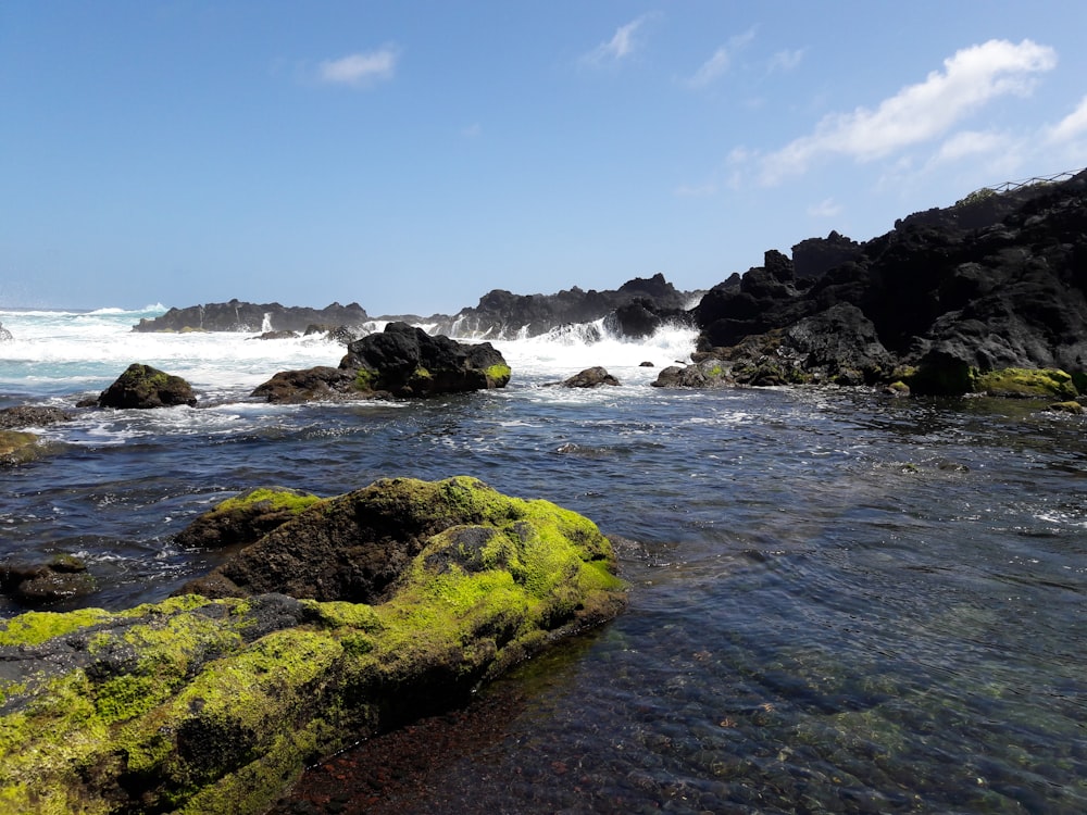 brown rock formation on sea under blue sky during daytime