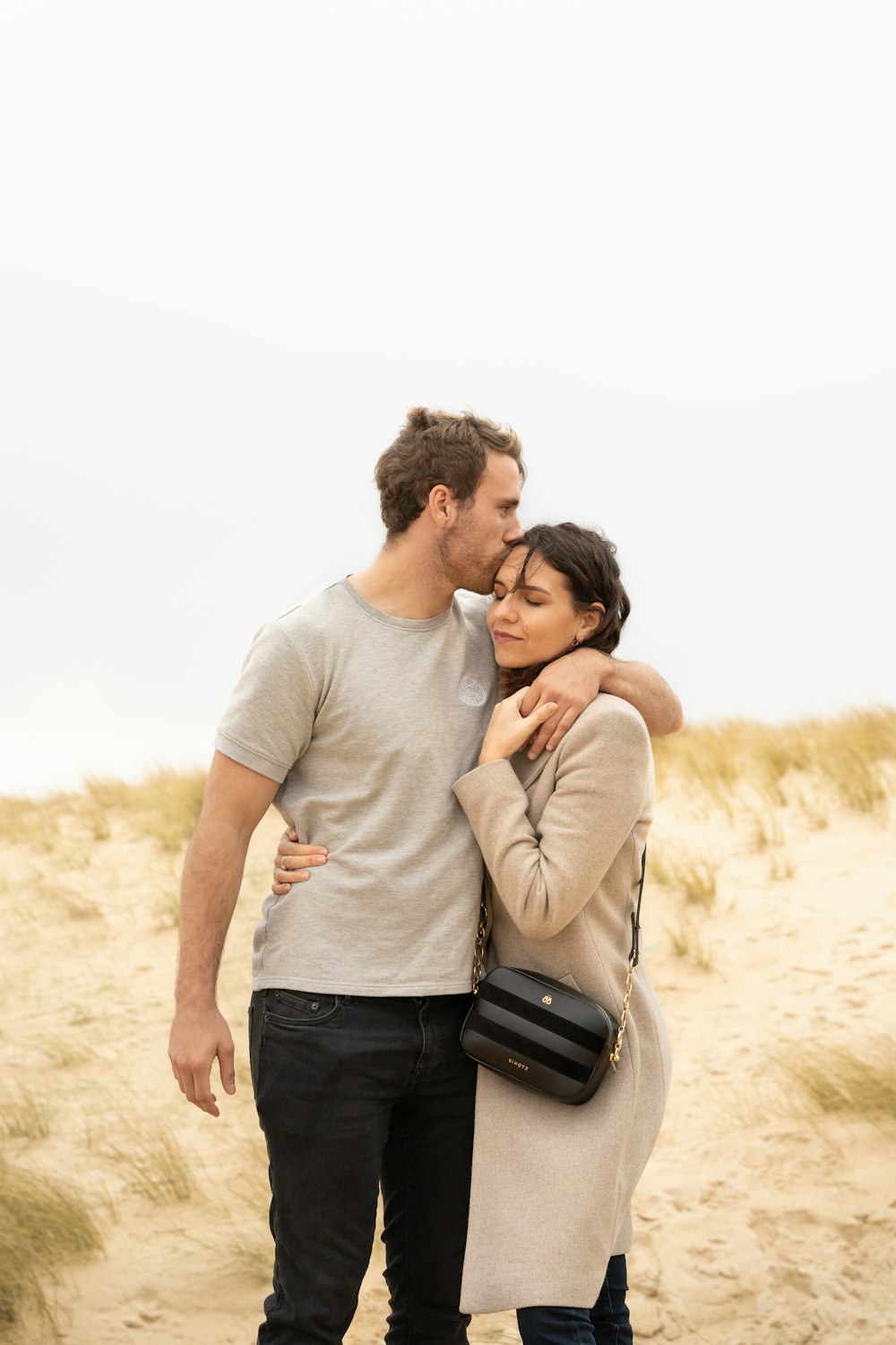 man in gray crew neck t-shirt kissing woman in black and white stripe long sleeve