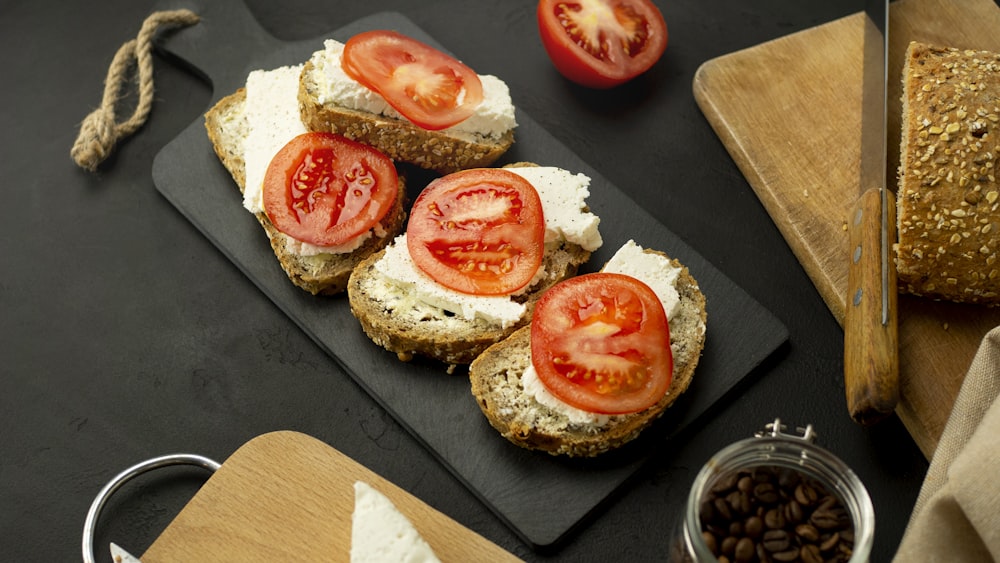 two burger with tomato and cheese on black tray