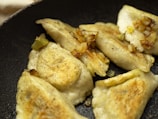A close-up of golden-brown pierogis on a plate.