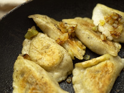 A close-up of golden-brown pierogis on a plate.