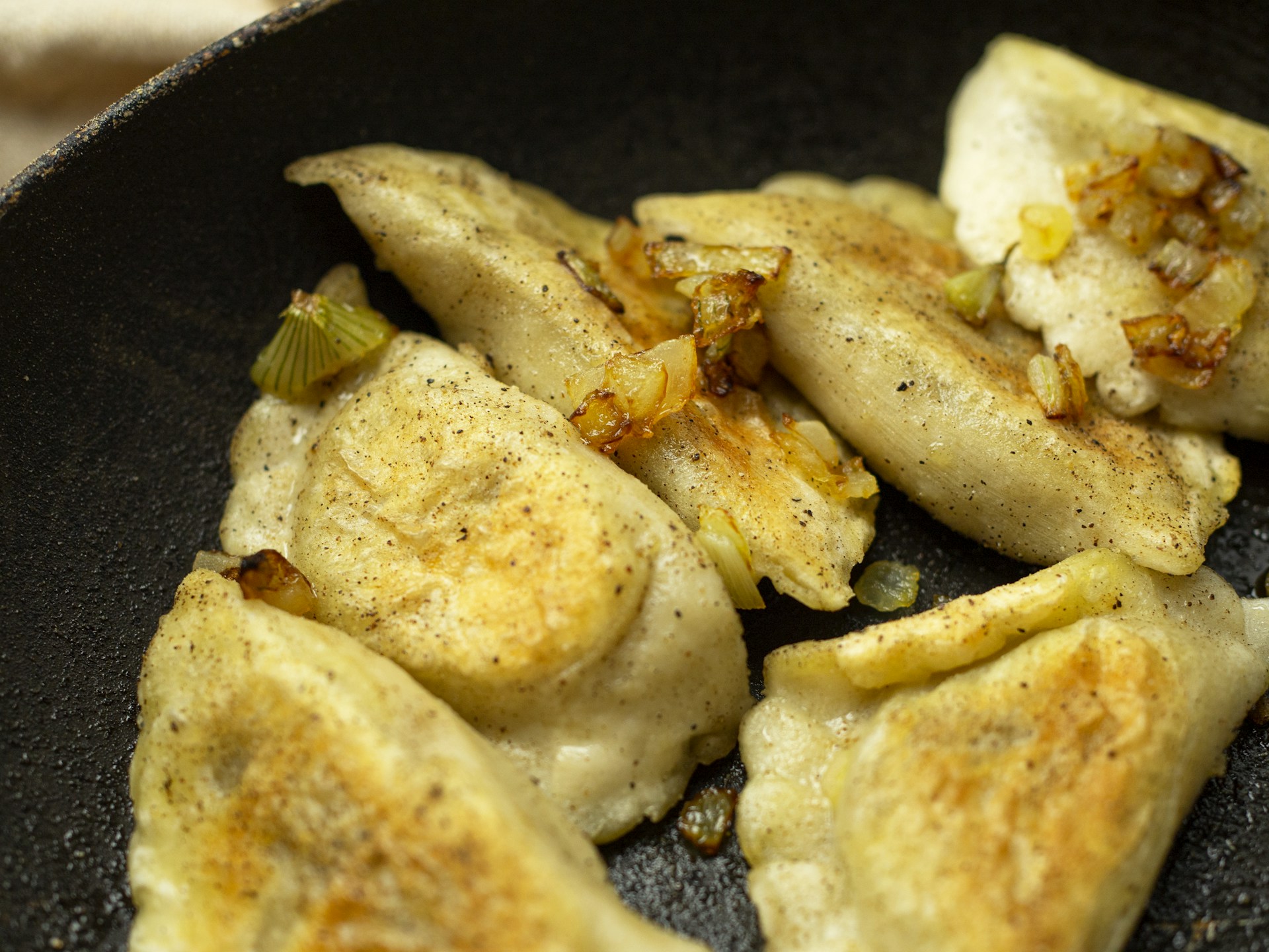 A warm, inviting shot of golden fried dumplings resting on a bamboo steamer with a side of soy dipping sauce.