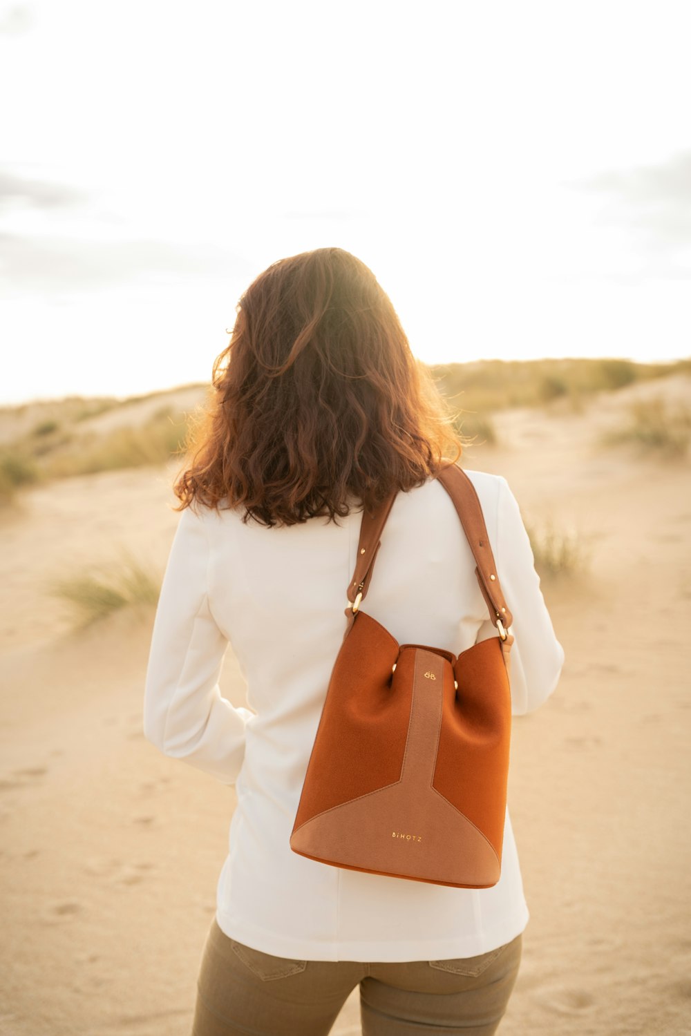 woman in white blazer and orange bikini bottom standing on beach during daytime