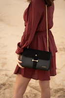 woman in red long sleeve shirt and black skirt carrying black leather handbag