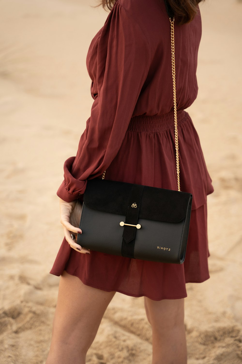 woman in red long sleeve shirt and black skirt carrying black leather handbag