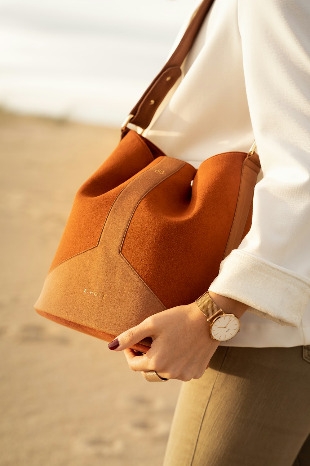 person in white dress shirt holding brown leather handbag