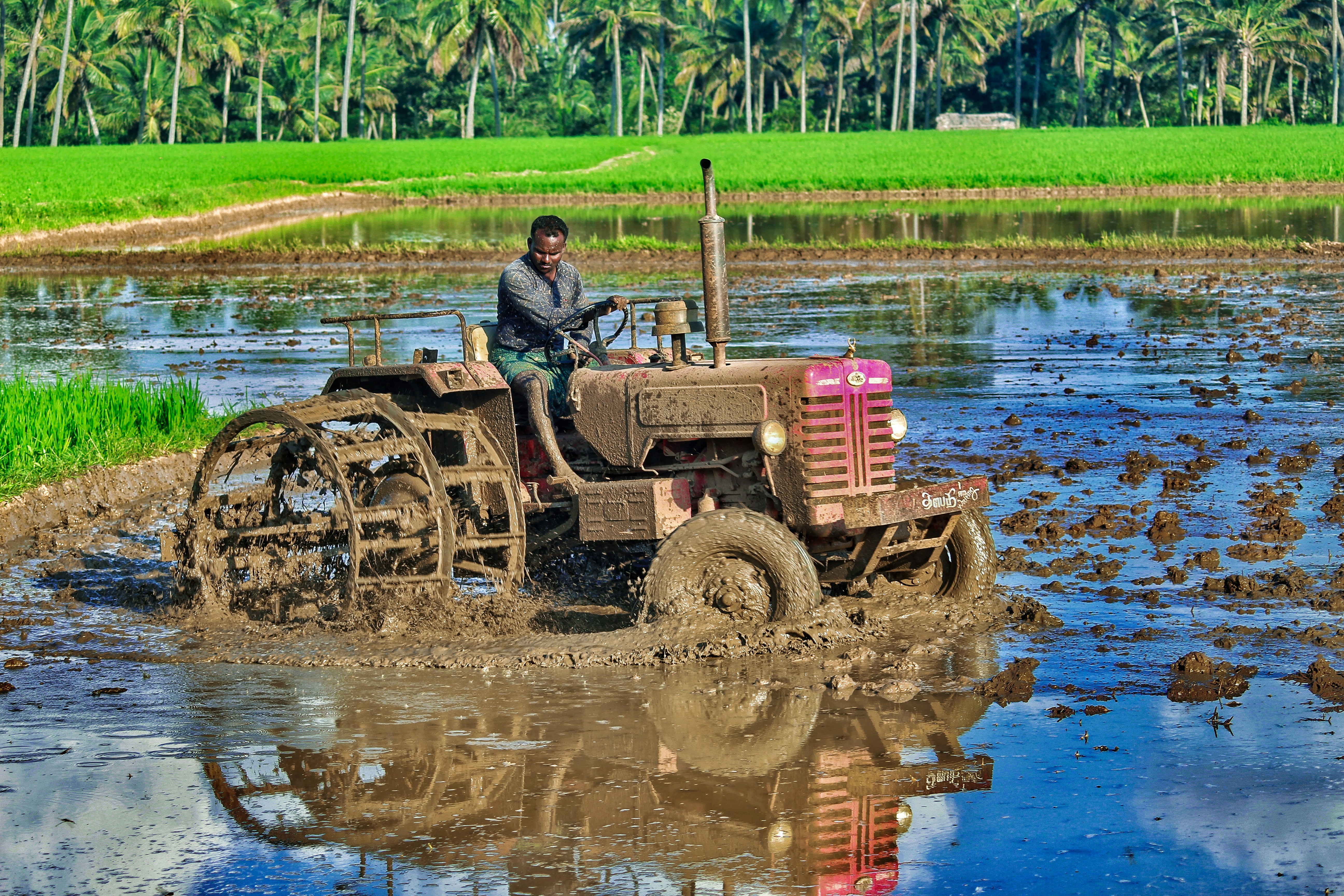 man in black jacket riding red tractor on river during daytime