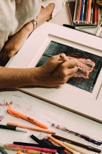 An artist's hand sketching a colorful creative illustration with pencils and markers.