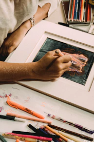 Close-up of hands sketching vibrant artwork with colored pencils.