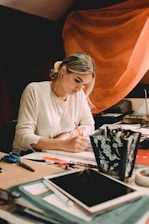 woman in white long sleeve shirt writing on white paper