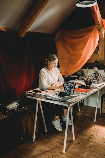 Portrait of Jessy Piacentini in a cozy, well-lit workspace filled with books and creative tools.