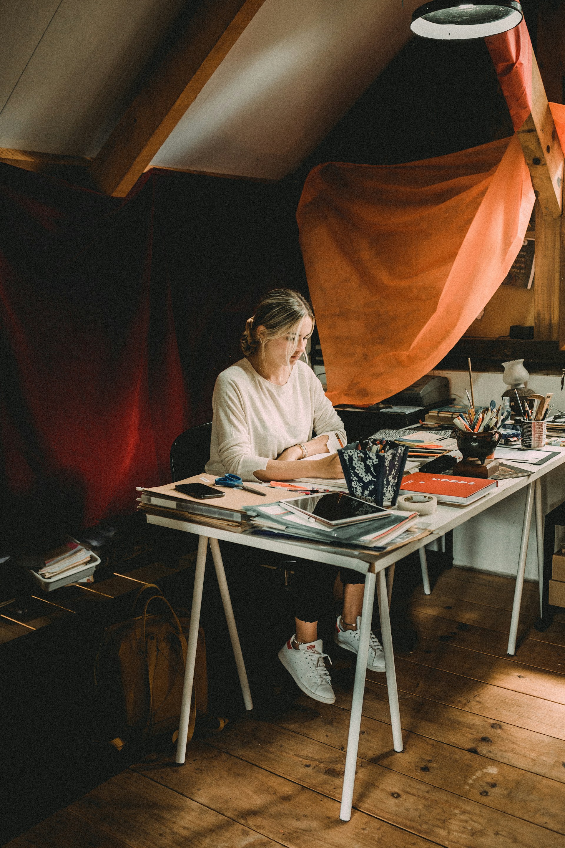 A candid shot of the founder jotting down notes in a cozy, cluttered workspace filled with quirky decor.