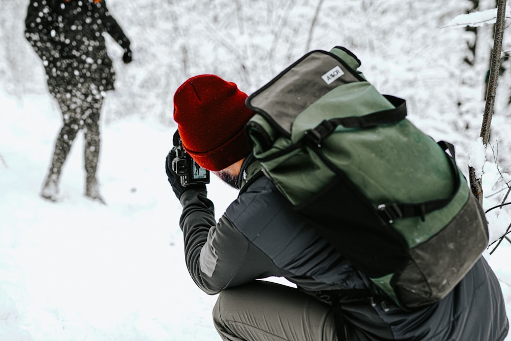 woman in black jacket and red knit cap holding black dslr camera