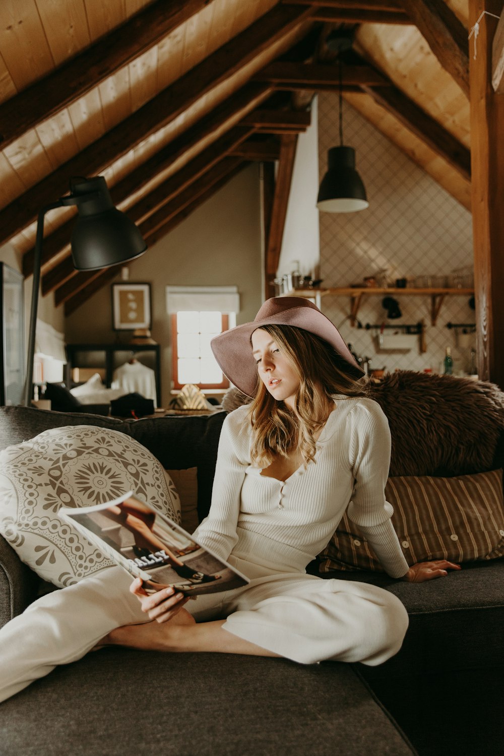 woman in white long sleeve shirt and white pants sitting on brown sofa