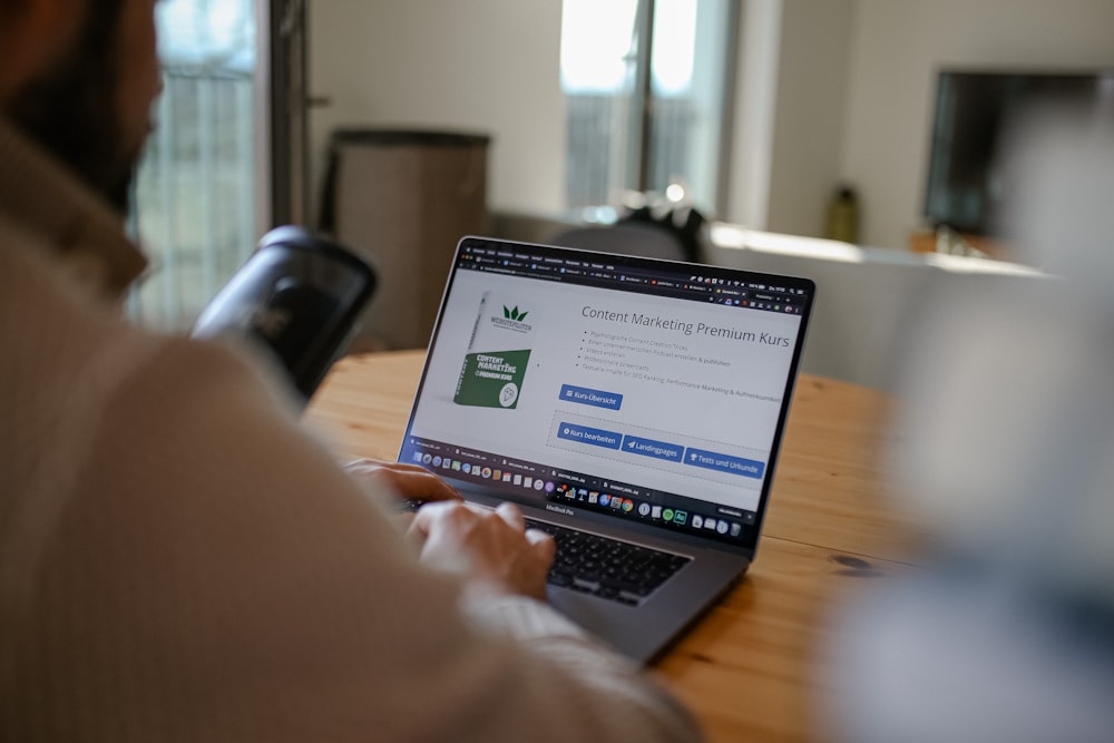 person using macbook pro on brown wooden table