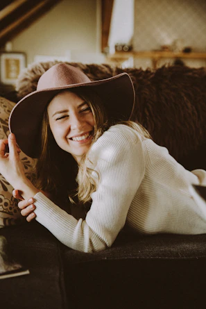 A relaxed model smiling while seated in a cozy room, dressed in a pastel Kaulika daster