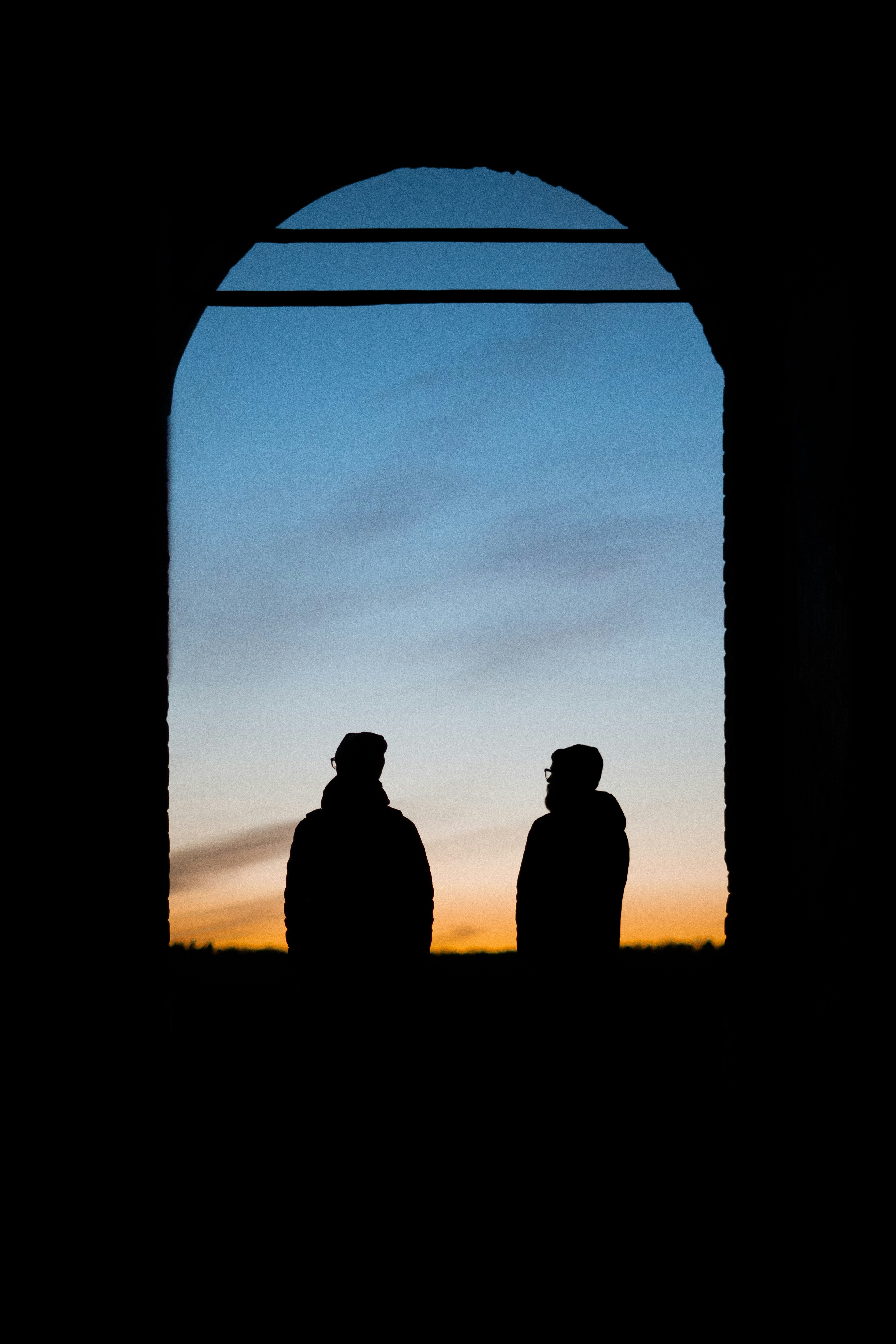 silhouette of 3 person standing on the window during sunset