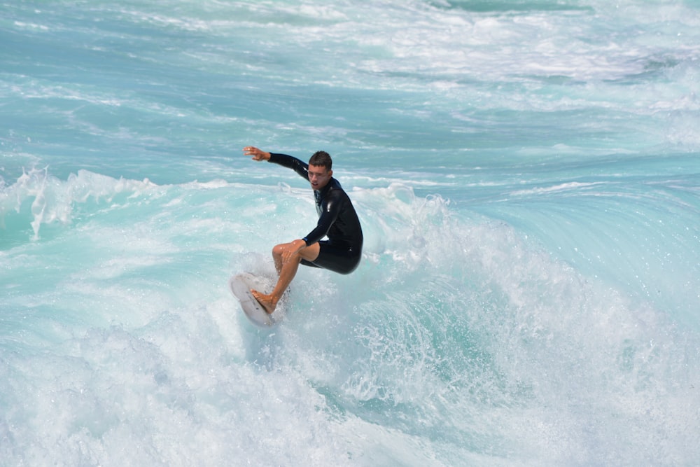 woman in black wetsuit surfing on sea waves during daytime