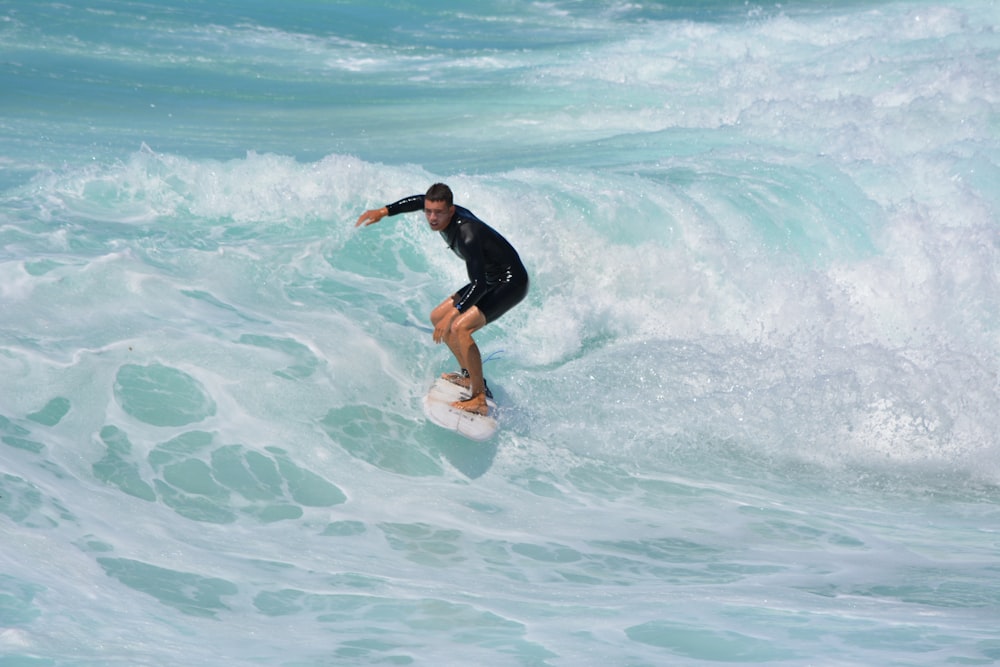 man in black shirt and shorts surfing on sea waves during daytime