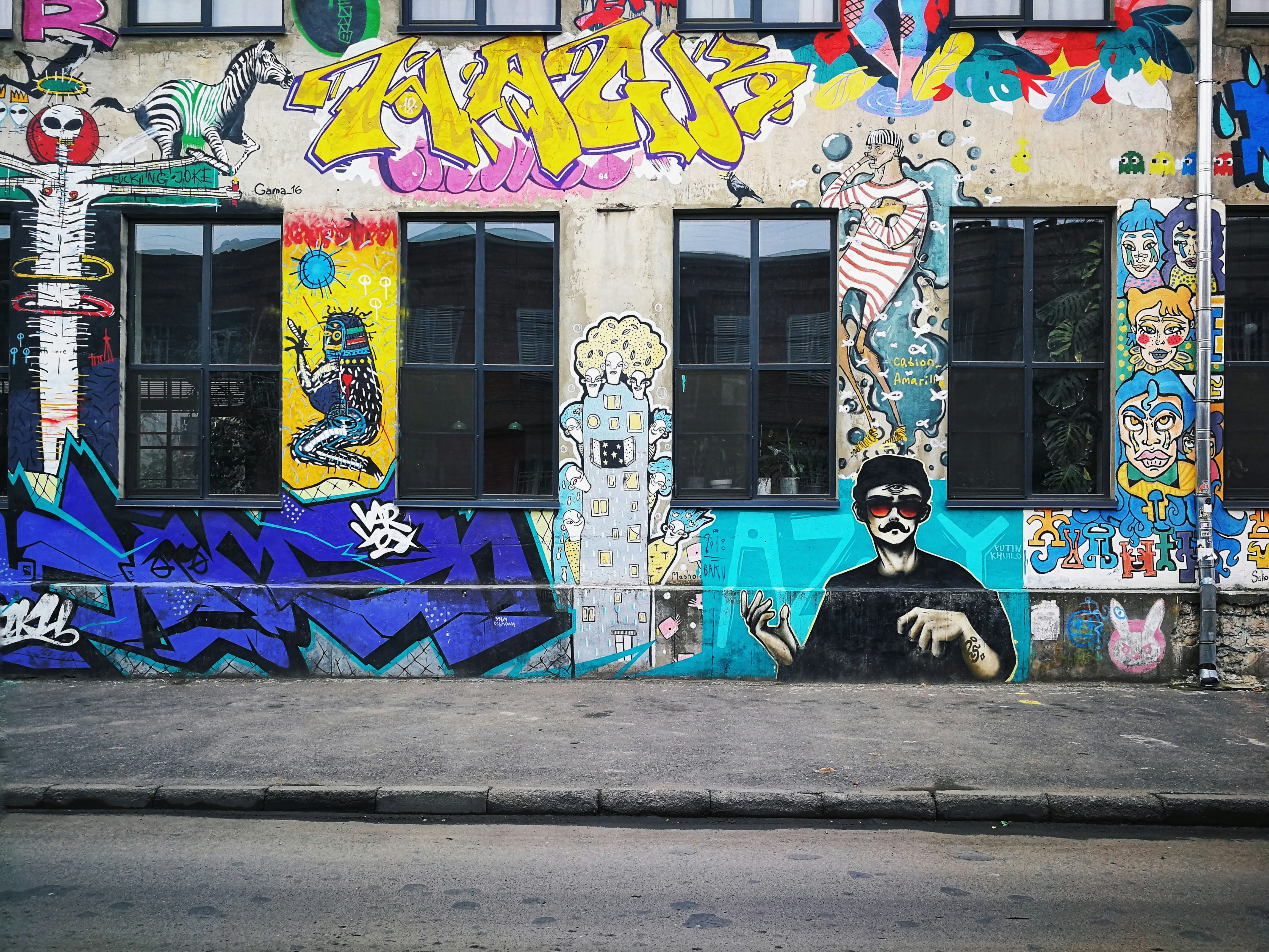 man in black and white jacket sitting on concrete pavement