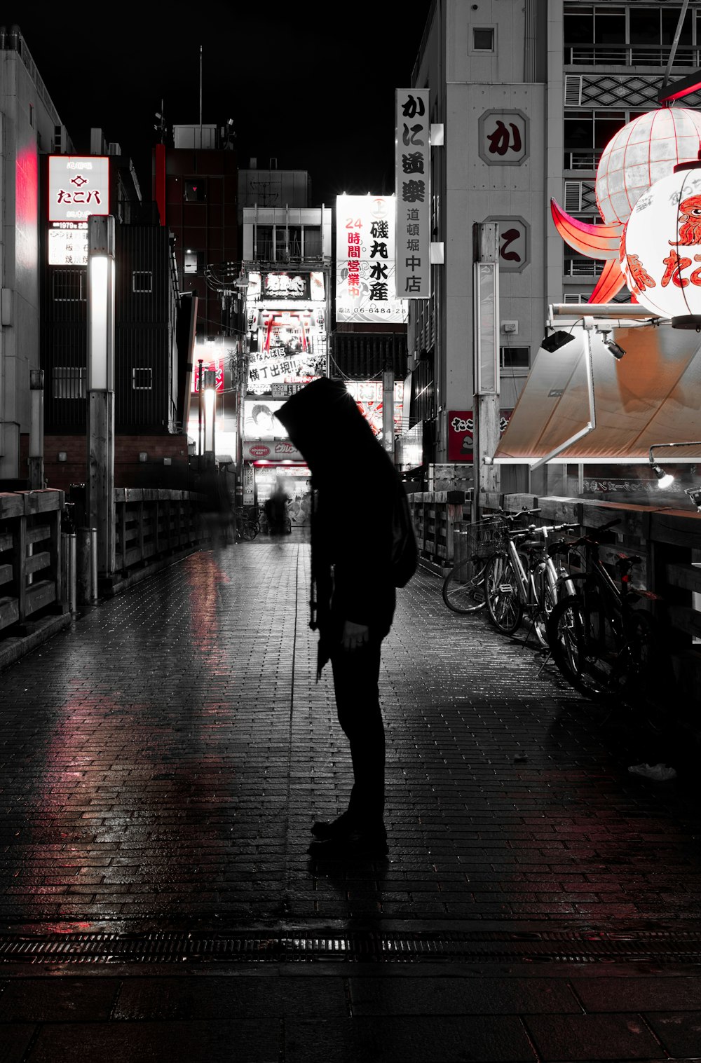 Person im schwarzen Kittel geht nachts auf dem Bürgersteig