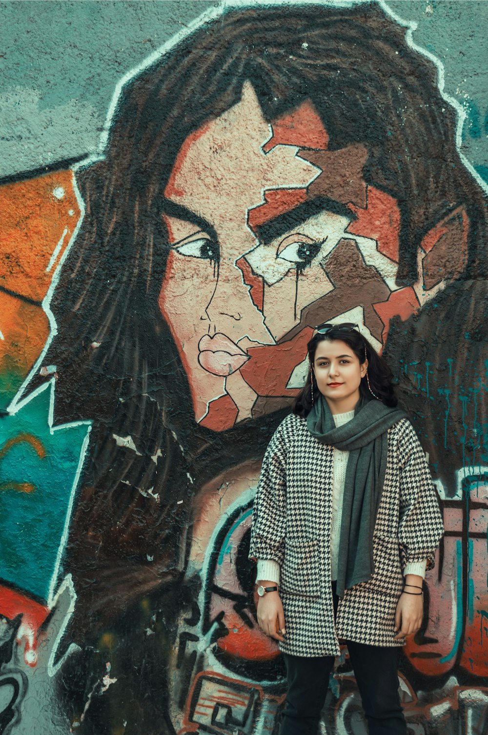 woman in black and white checkered dress shirt standing beside wall with graffiti