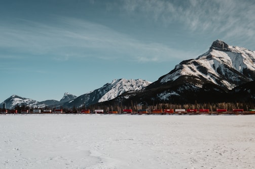 A freight train loaded with containers moving through a mountainous landscape.