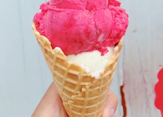 person holding ice cream cone with pink ice cream