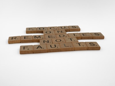 Wooden letter tiles arranged to spell out the phrase 'Focus on remedies not faults' on a plain white background.