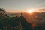 A traveler standing on a mountain peak at sunrise, soaking in the view.