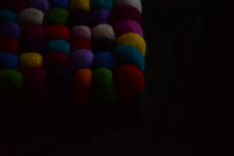A vibrant close-up of colorful handmade yarn pom-poms scattered on a wooden table.