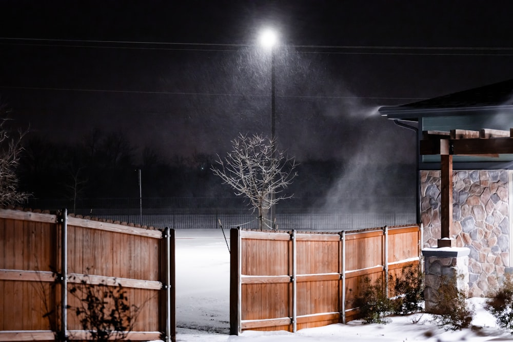 brown wooden fence on snow covered ground during night time