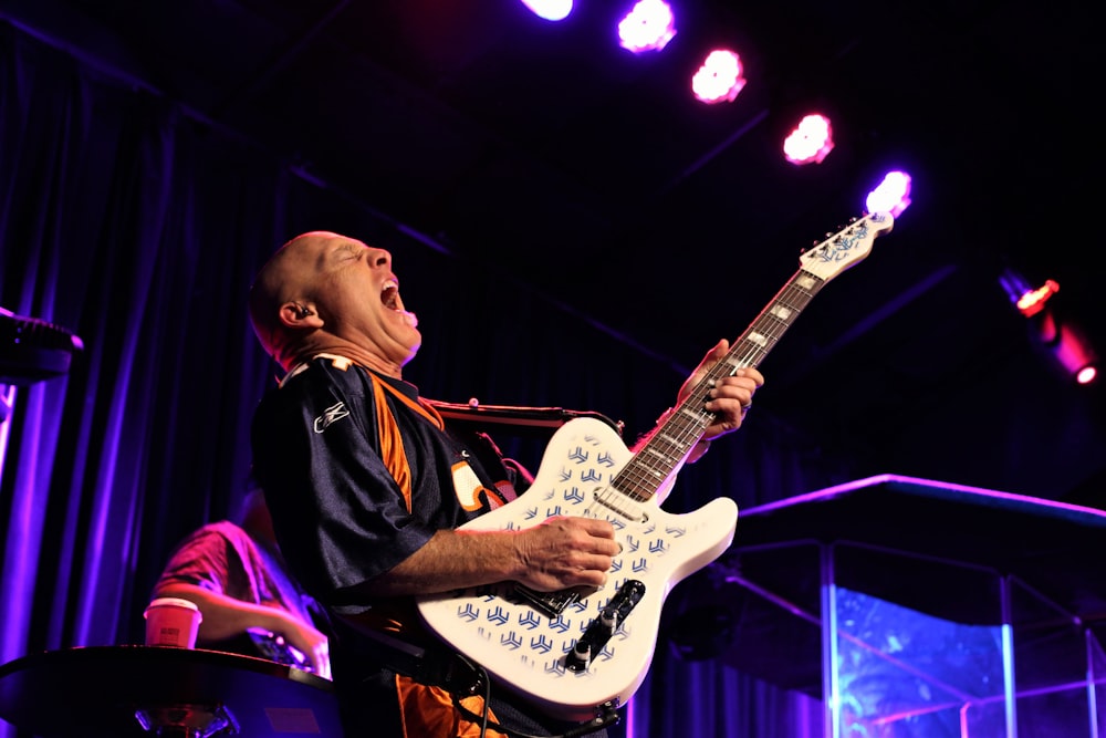 woman in black jacket playing white electric guitar