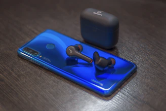 A hands-free Bluetooth headset resting neatly beside a charging phone.