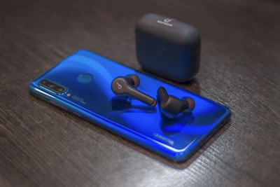 A hands-free Bluetooth headset resting neatly beside a charging phone.