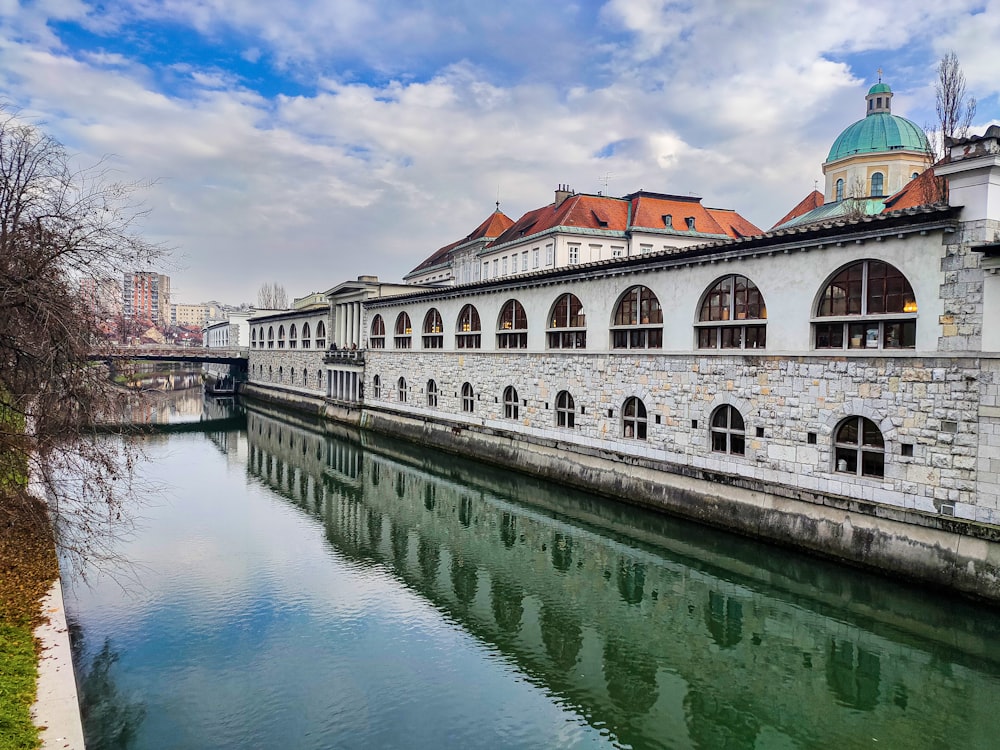 white and brown concrete building beside body of water under blue sky during daytime