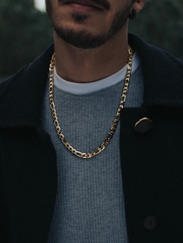 man in black coat wearing gold necklace
