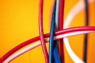Vibrant charging cables tangled artistically on a bright background.