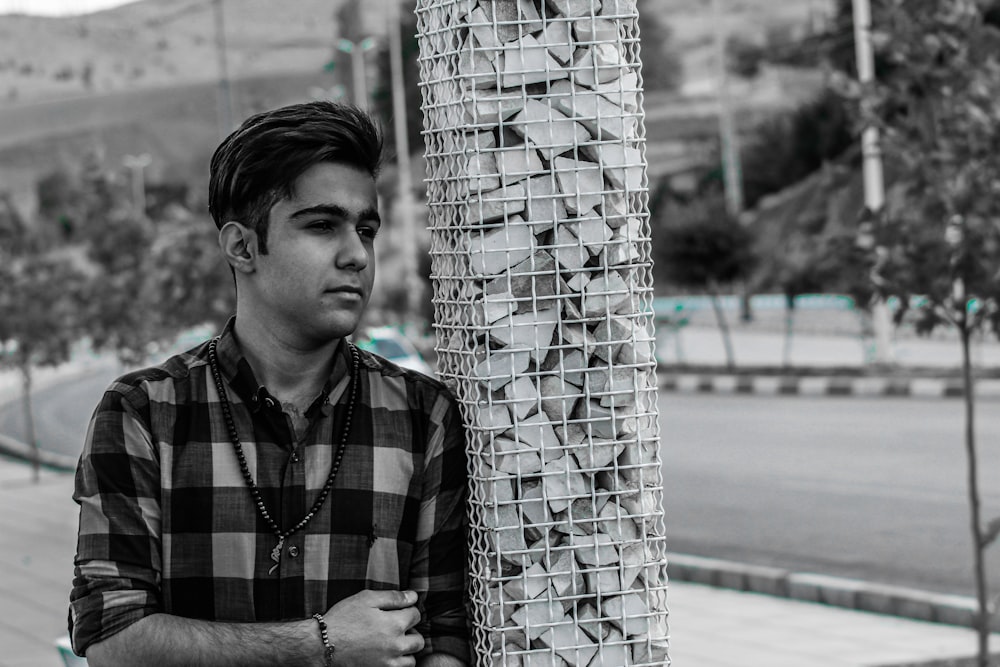 man in black and white checkered button up shirt standing beside white and black wall